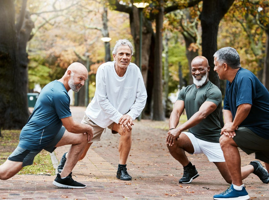 Four men of diverse ages performing lunges outdoors in a park during autumn