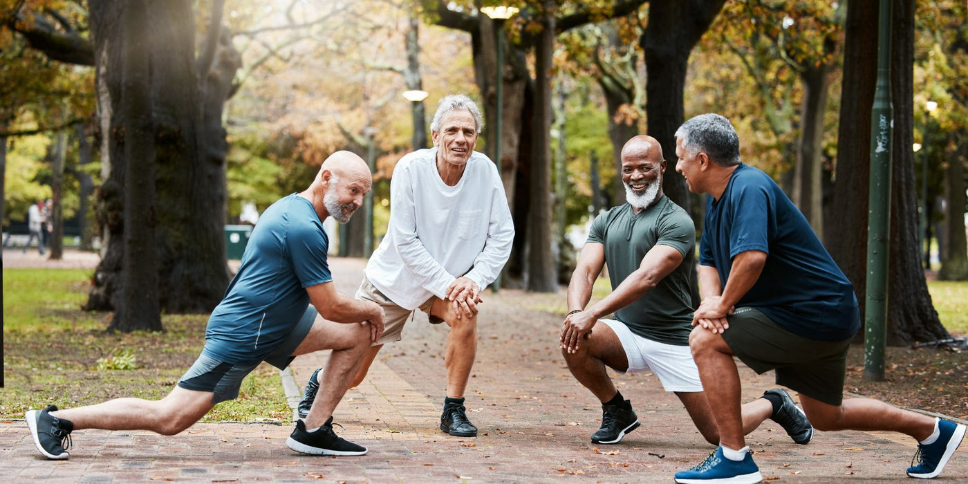 Four men of diverse ages performing lunges outdoors in a park during autumn