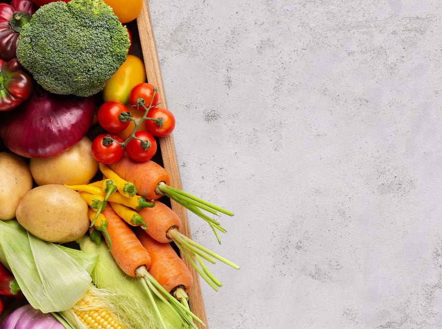 Wooden crate overflowing with fresh vegetables including broccoli peppers tomatoes and carrots.