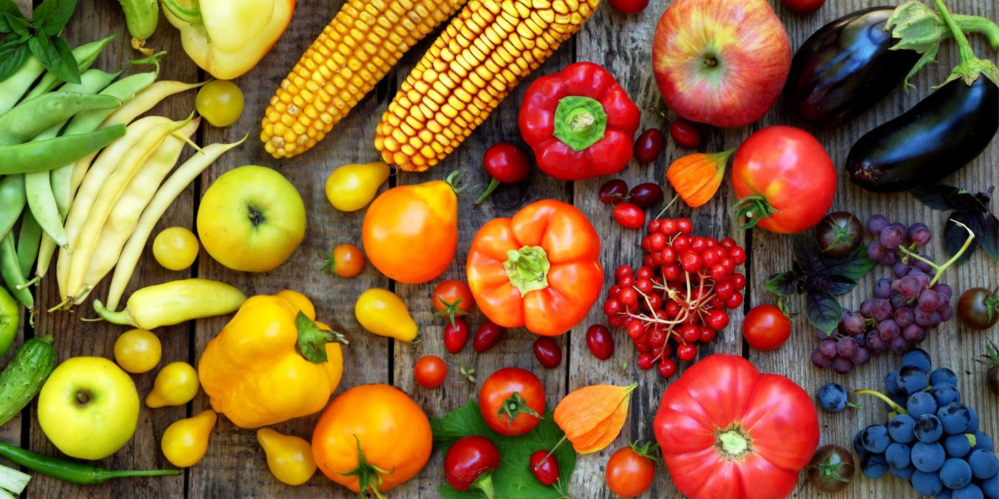Colorful assortment of fresh fruits and vegetables spread on a rustic wooden surface