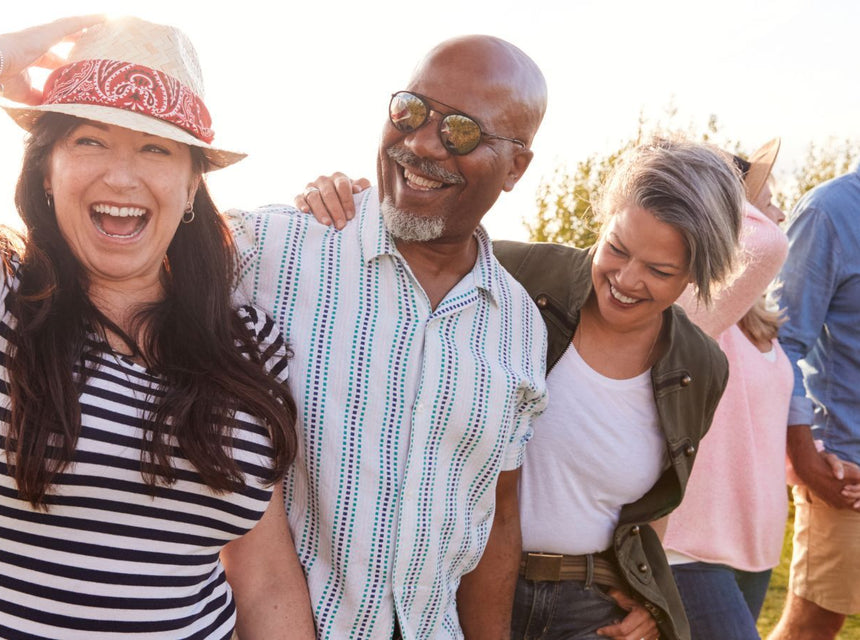 Smiling diverse group of adults walking outdoors in a sunny field representing healthy ageing.