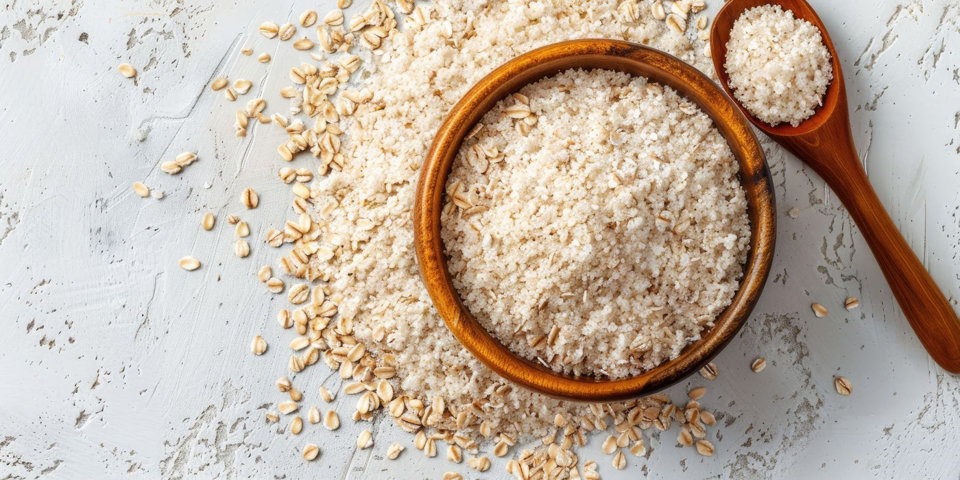 Wooden bowl of oats with a spoon and scattered grains on a light surface