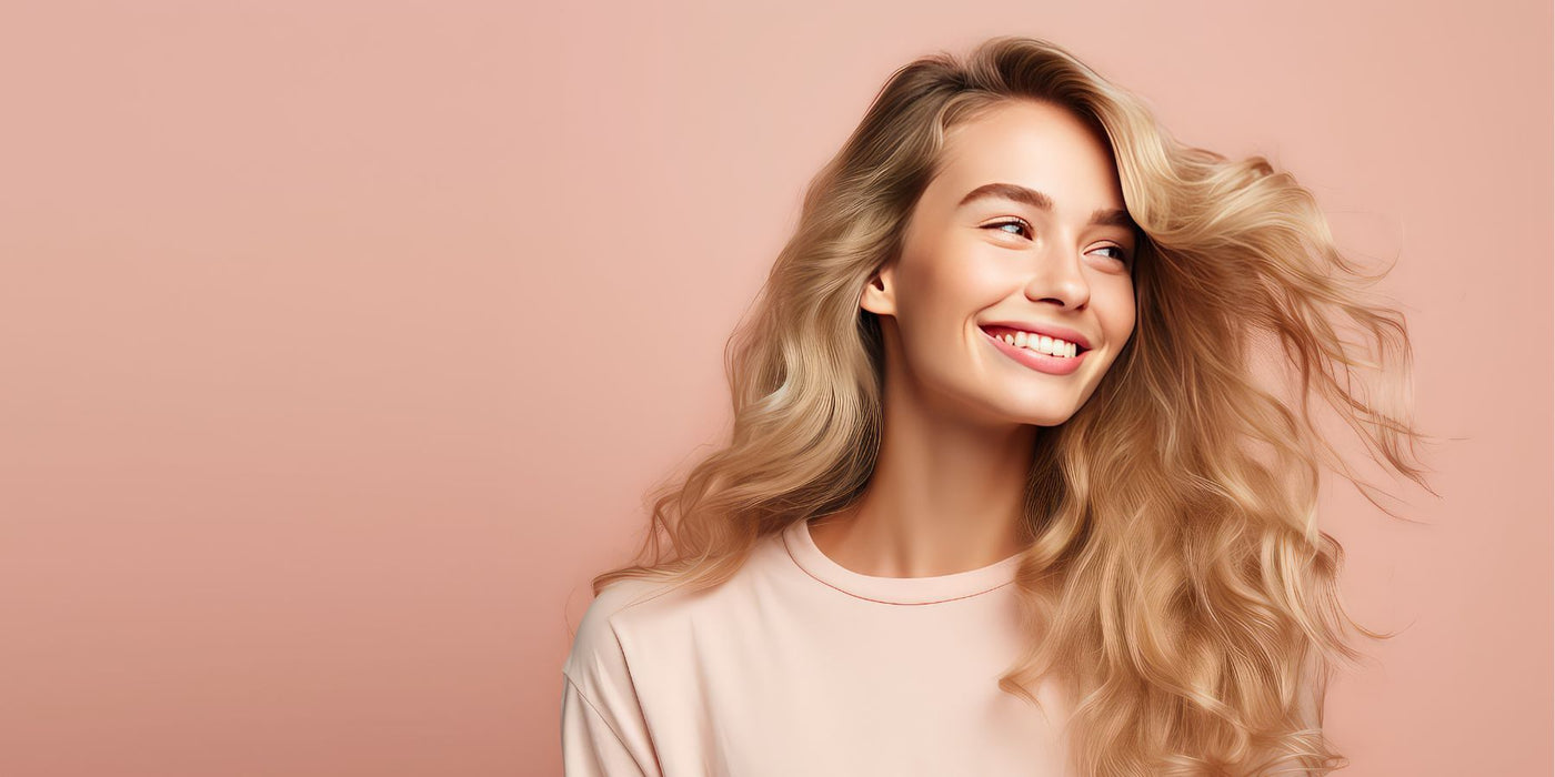 Smiling woman with long blonde hair against a soft peach background.