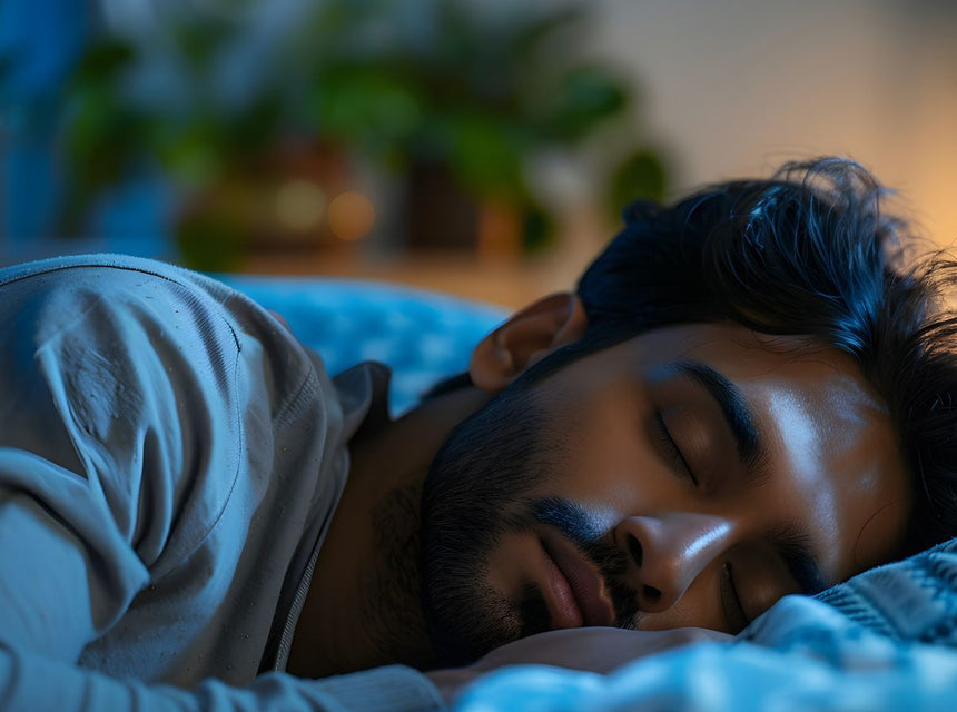 Man sleeping soundly on a bed in a blue lit bedroom