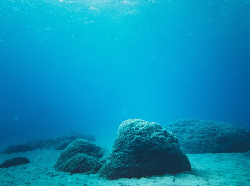 Underwater scene with large rocks on the seabed and clear blue water