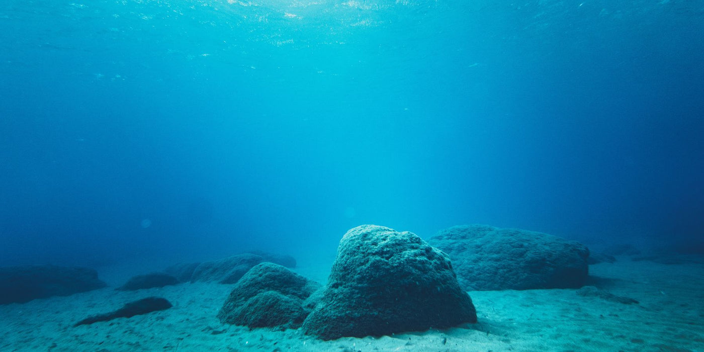 Underwater scene with large rocks on the seabed and clear blue water