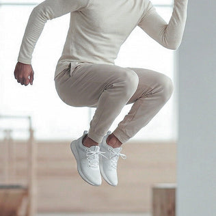 Athlete in beige athletic wear leaps midair indoors capturing energy