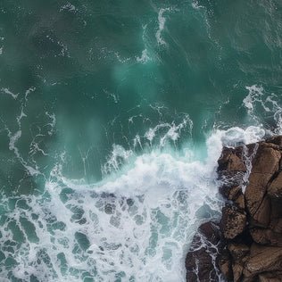 Aerial view of turquoise sea waves crashing onto a rocky shoreline