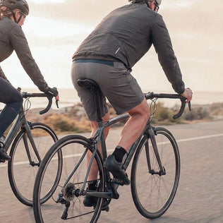 Two cyclists ride road bikes along a desert highway
