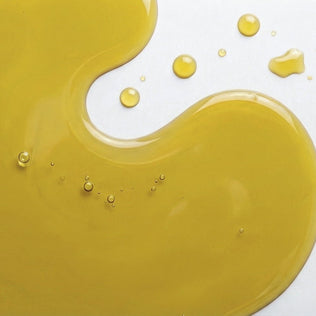 Golden omega 3 fish oil spill on a white surface with bubbles.