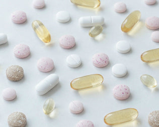 Assorted pills and capsules scattered on a pale surface as a visual for the Product A-Z collection