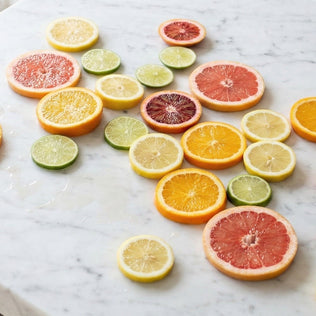 Assorted citrus fruit slices including orange lemon lime and grapefruit arranged on a marble surface.